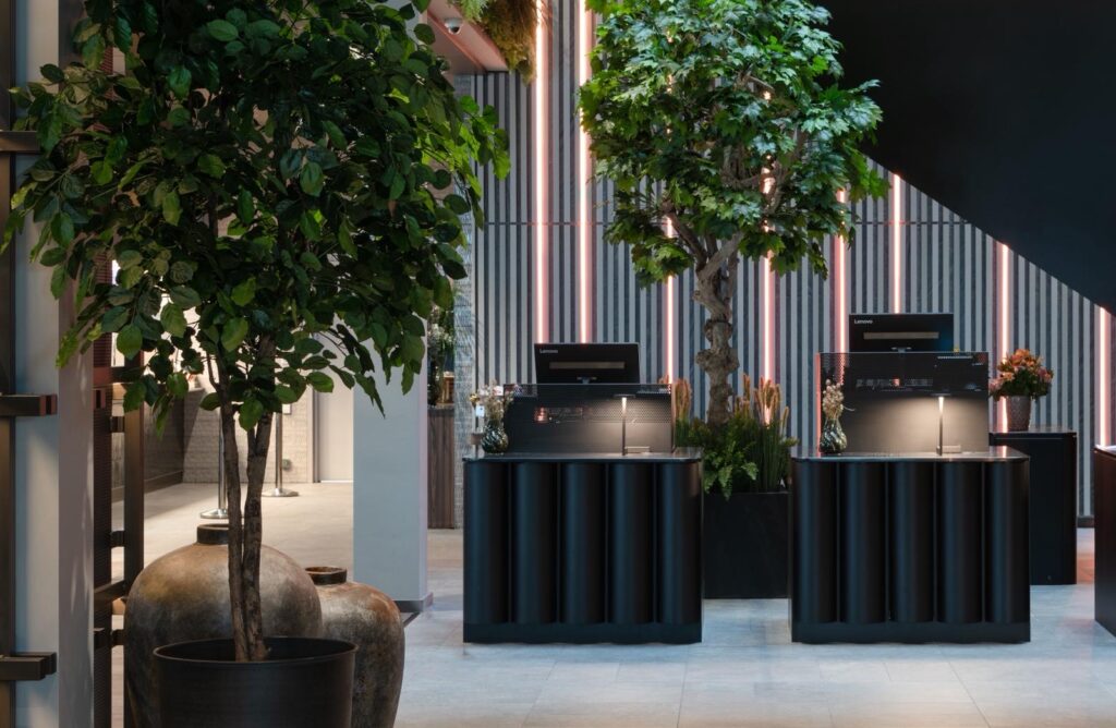 Två stora konstgjorda träd i mottagningsmiljö/lobby — exempel på hur ett stort träd inomhus skapar wow-effekt